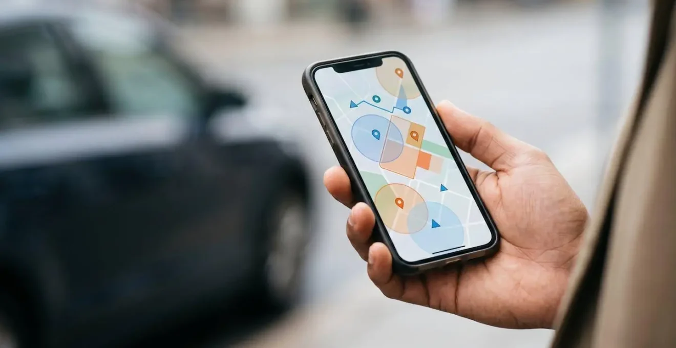 Main tenant un smartphone en extérieur capturant une scène d'accident avec interface de géolocalisation abstraite